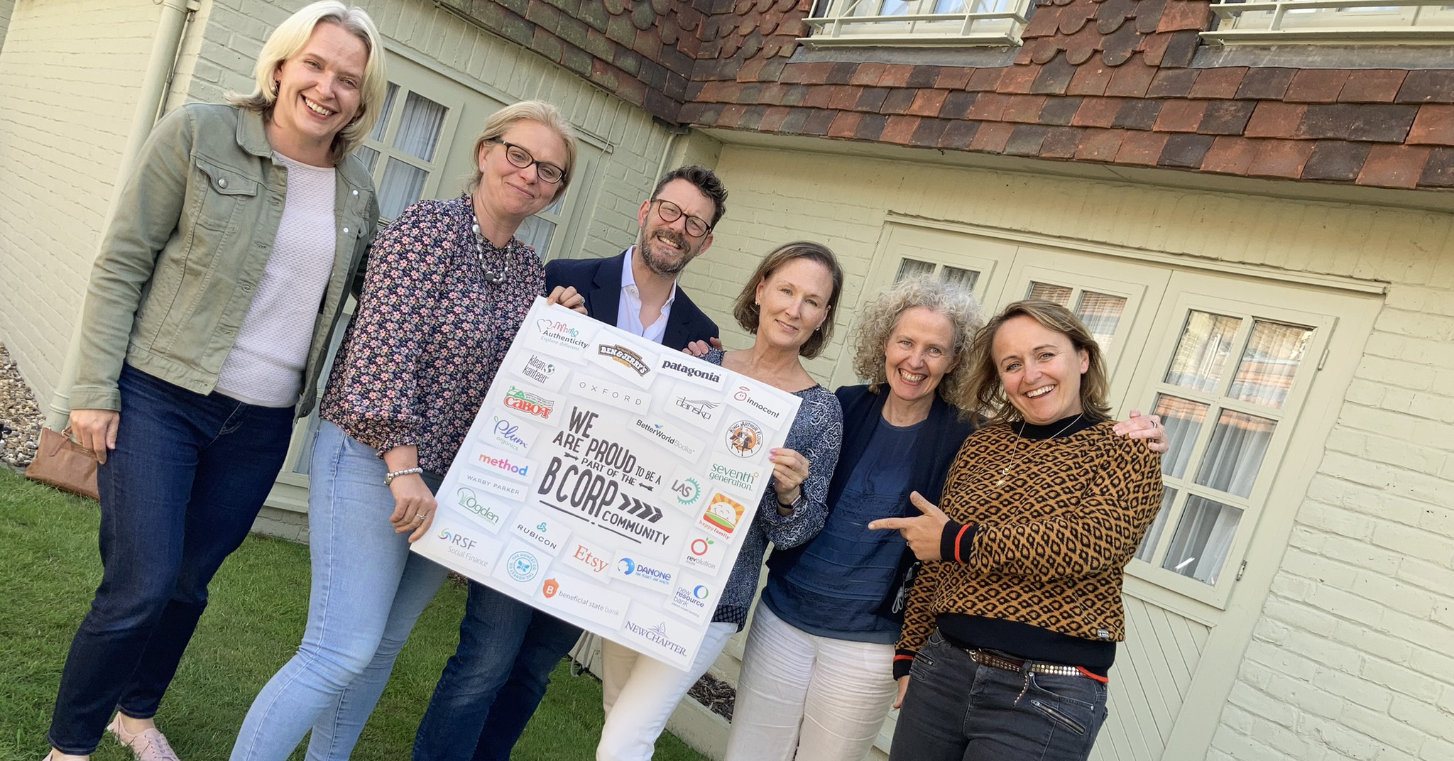 The Oxford SM team holding their B Corp certification poster smiling at the camera