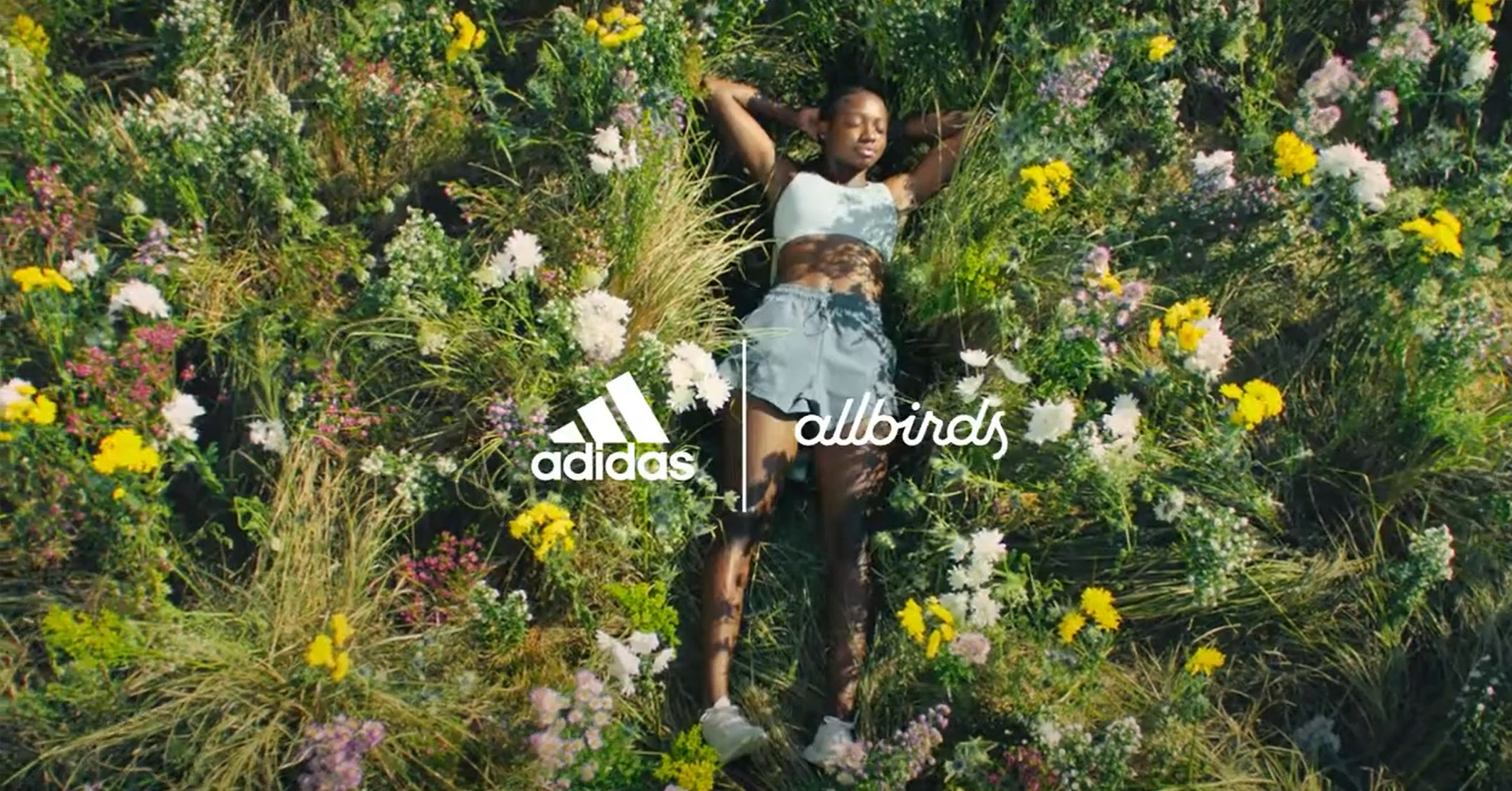 A woman laying down in a field of flowers for an adidas campaign