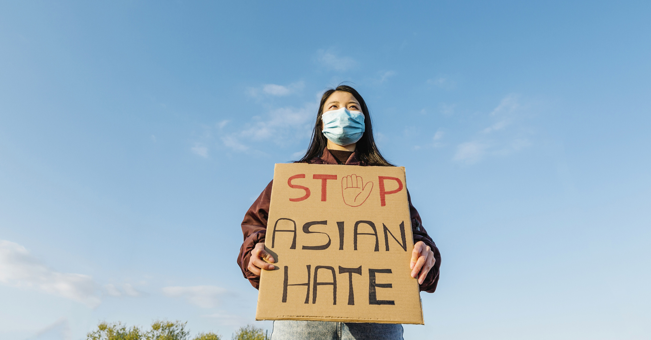 A woman wearing a face mask holding a sign saying 